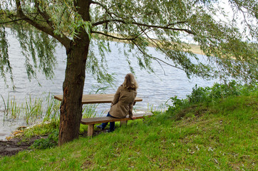 woman sit wooden bench willow tree admire lake © sauletas