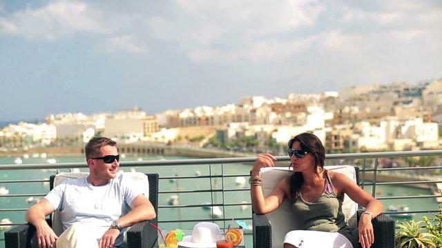 Happy couple with exotic drinks relaxing on the terrace, crane s