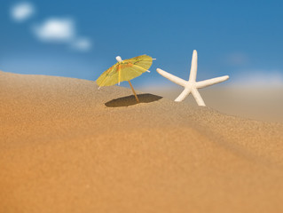 Fototapeta na wymiar Umbrella Beach stoi w piasku z Rozgwiazda koło