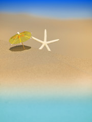 Fototapeta na wymiar Beach Umbrella standing in the Sand with a Starfish near