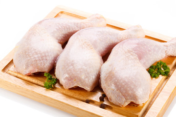 Raw chicken legs on cutting board on white background