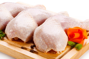 Raw chicken legs on cutting board on white background