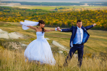 bride and groom outdoor standing in a yellow field hug, portrait