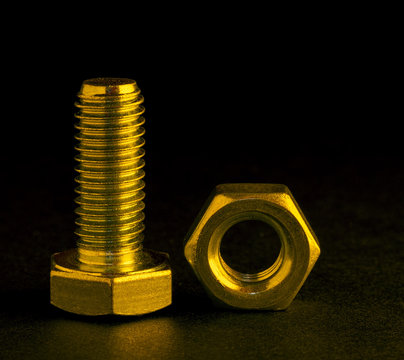 Nut And Bolt With Gold Lighting On Black Background