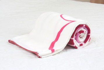 Small fleece blanket on white bed