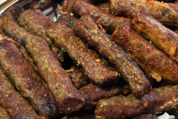Pile of roasted long cylindric meatballs (soutzoukaki).