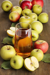 Useful apple juice with apples around on wooden table