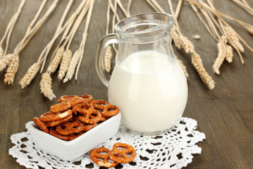 Tasty pretzels in white bowl and milk jug