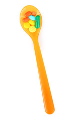 Plastic spoon with color pills, isolated on white