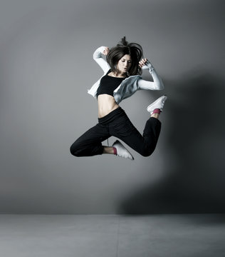 A young and fit Caucasian woman jumping in sporty clothes