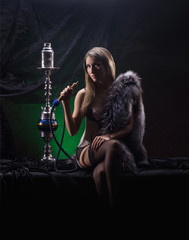 A young and sexy blond woman smoking a hookah