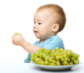 Little boy is eating grapes