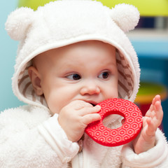 little baby baby chews on a soft plastic toy