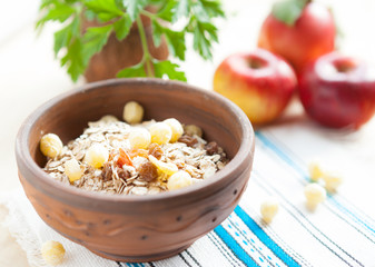 Muesli in a ceramic bowl and fresh apples in the background