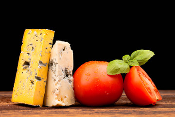 Various types of cheese and tomatoes isolated on black