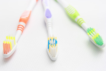 Closeup of three toothbrushes of different colors on the shelf.
