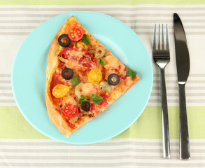 plate with a slice of delicious pizza on tablecloth close-up