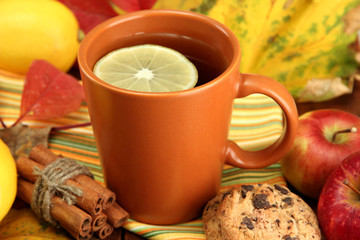 cup of hot tea and autumn leaves, on wooden table
