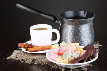 Cup of coffee with rahat delight and coffee pot on wooden table