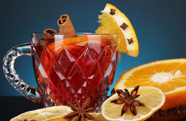 Fragrant mulled wine in glass with spices and oranges around