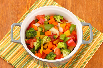 Vegetable stew in gray pot on color napkin on wooden background