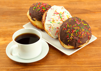 Tasty donuts on color plate on wooden background