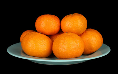 Tasty mandarines  on color plate isolated on black