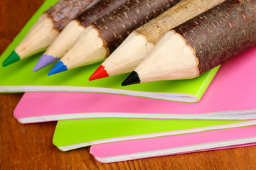 Colorful wooden pencils with exercisebooks on wooden table