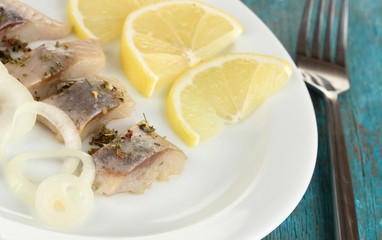 Dish of herring on plate on blue wooden table close-up