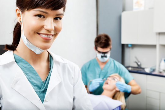 Female Hygienist With Dentist Working In The Background