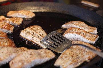 pieces of salmon fry in a large frying pan