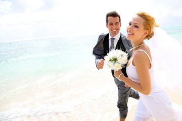 Just married couple running on a sandy beach