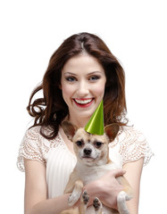 Pretty woman hugs a straw-colored small dog in cap
