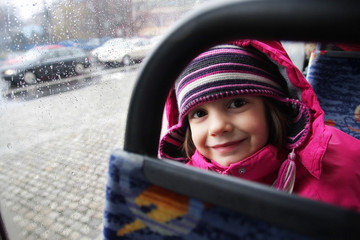 Uśmiechnięta dziewczynka jedzie autobusem - obrazy, fototapety, plakaty