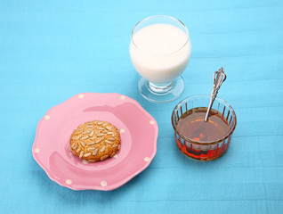 pink plate with sunflower seed cookie with honey and milk