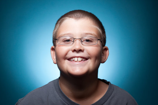 A portrait of a young boy with glasses smiling