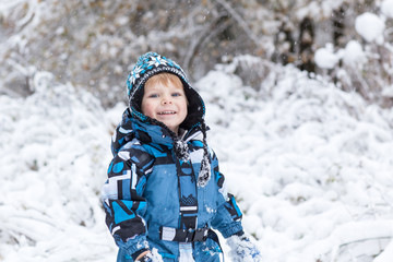 Fototapeta na wymiar Toddler boy having fun with snow on winter day