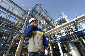 oilk and gas refinery with worker talking in phone