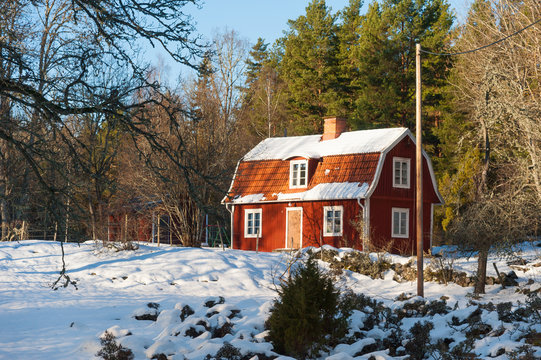 Typical red wooden house in Sweden in wintry landscape