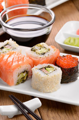 Mixed sushi on a white plate with soy sauce wasabi and  ginger