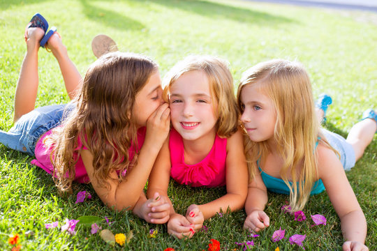 children girls playing whispering on flowers grass