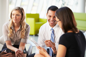 Businesspeople With Digital Tablet Having Meeting In Office