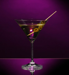 Martini glass and olives on dark background