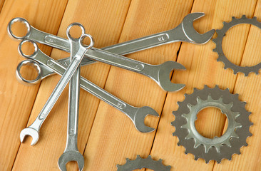 Metal cogwheels and spanners on wooden background