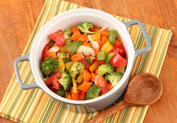 Vegetable stew in gray pot on color napkin on wooden background