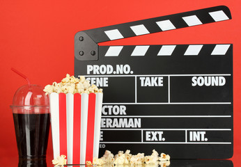 Fototapeta na wymiar Film Klaps, cola i popcorn na czerwonym tle