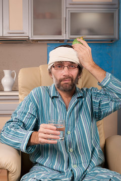 mature man sitting in chair with glass of water