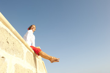 Happy Mature woman sitting on wall