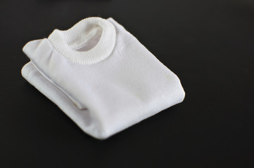 White t-shirts folded on a black background.