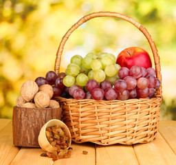 Grape in basket with nuts on wooden table